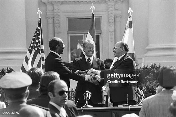 Egyptian President Anwar Sadat, President Jimmy Carter and Israeli Prime Minister Menachem Begin share a three way handshake after the signing of the...