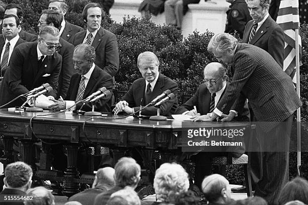 Washington, DC- As President Jimmy Carter looks on, Egyptian President Anwar Sadat and Israeli Prime Minister Menachem Begin put their signatures on...