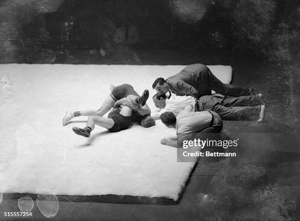 While the two judges and referee look closely, Herman Pihlajamaki of Finland attempts to pin Einar Karlsson of Sweden during their bantamweight bout...