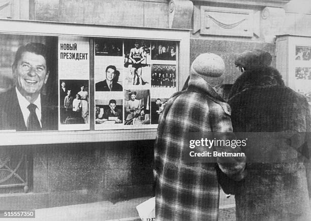 Muscovites stop and glance at a display of photographs of President-Elect Ronald Reagan on outside wall of the U.S. Embassy here 11/5 following...