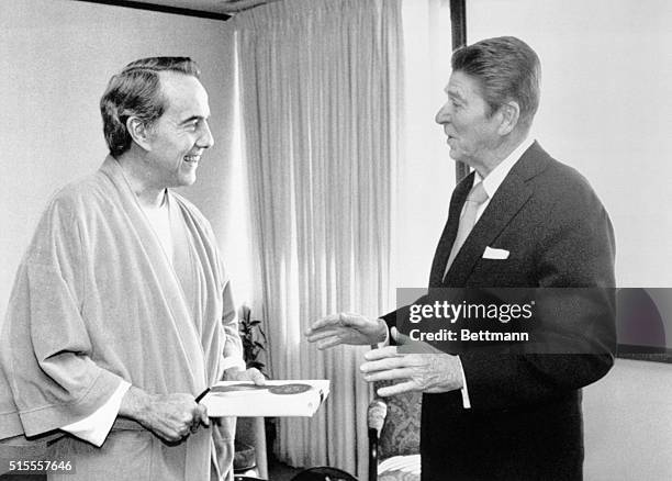 Washington: President Reagan presents a book to ailing Kansas Senator Robert Dole during his visit to Walter Reed Hospital where Dole is recovering...