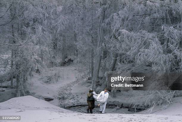 Rescuers removing body from campsite near Mount Saint Helens after the volcano erupted May 28. Ash covers the pine trees and ground like snow.