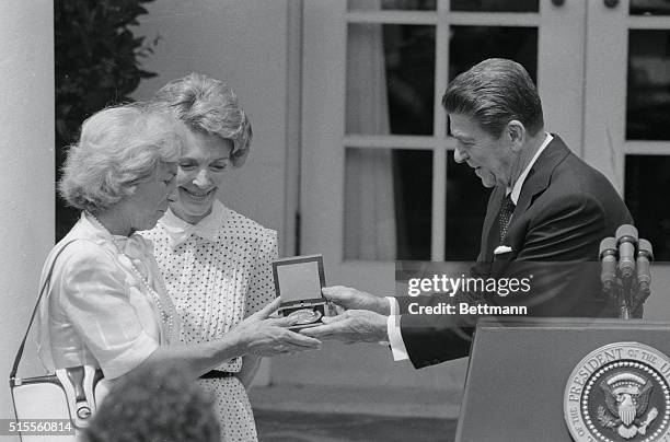 President Reagan presents a medal in honor of Robert F. Kennedy to his widow, Ethel, during a ceremony in the Rose Garden, as Nancy looks on.