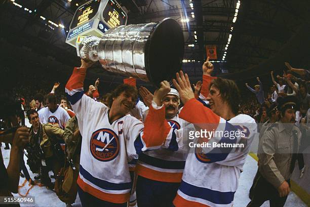 Denis Potvin, Bryan Trottier, and Mike Bossy, members of the New York Islanders hockey team, carry the Stanley Cup trophy in 1981.