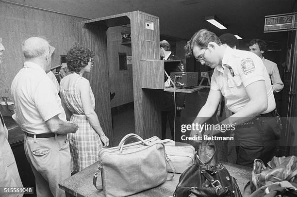 As her bag is searched by an officer, a spectator walks through a metal detector at State Supreme Court in Manhattan, June 22, before the beginning...