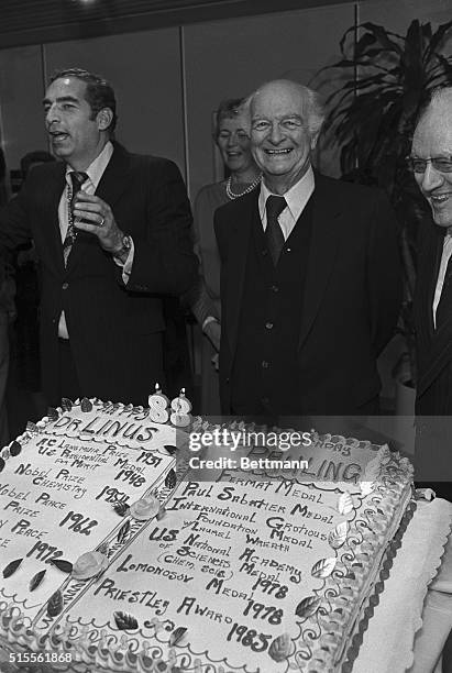 Two-time Nobel Prize winner Dr. Linus C. Pauling smiles as he stands in back of the cake presented to him while the crowd sings happy birthday. The...