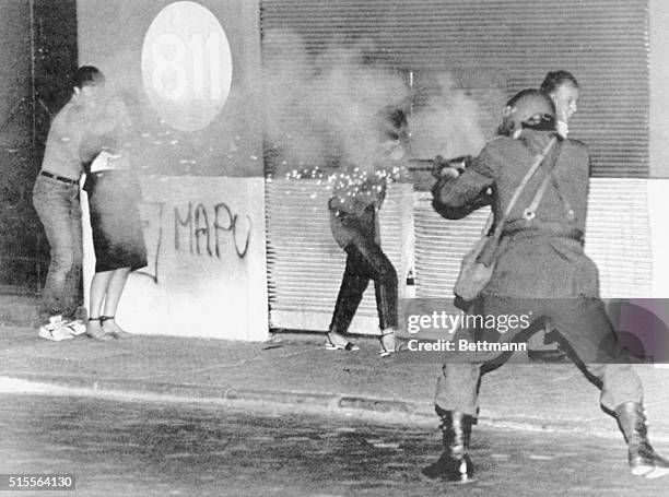 Santiago, Chile: A riot policeman fires tear gas at demonstrators as passersby cover their heads after a column of protesters tried to march on the...