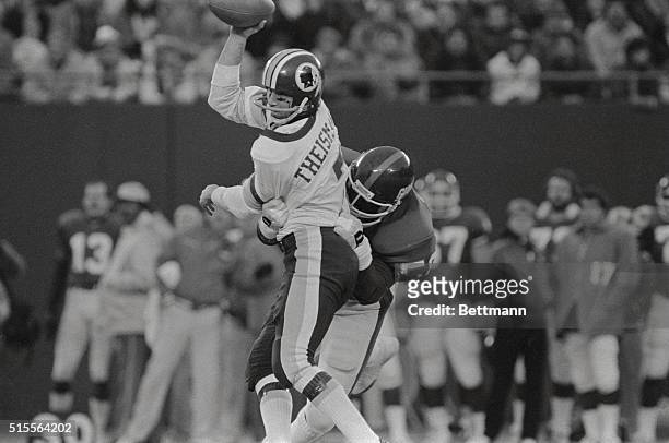 Washington Redskin's quarterback Joe Theismann looks around for a receiver, as he gets sacked by New York Giant's Lawrence Taylor during the first...