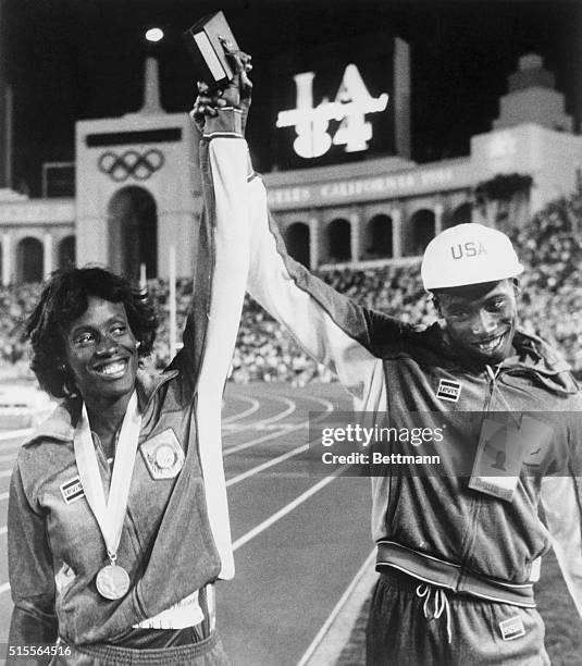 America's Al Joyner who won Gold in the Triple Jump 8/4 raises hand of his sister, Jackie who won a Silver in the Women's Heptathalon.