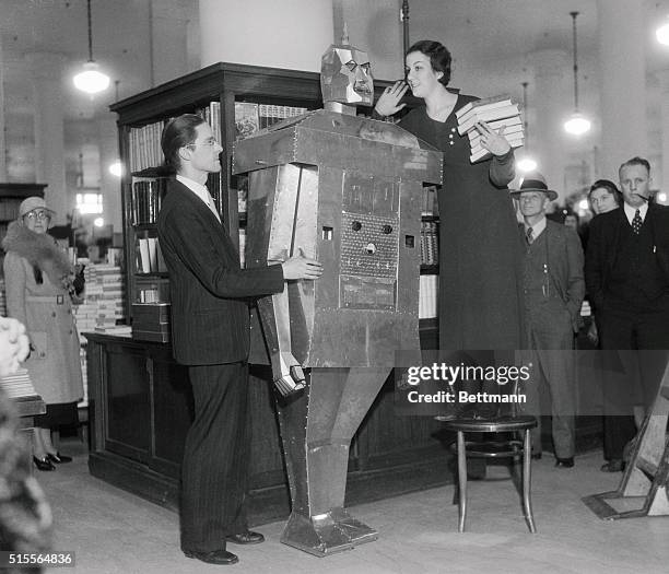 An Adventure Story? Miss Betty Davis tries out her sales talk on the robot invented by Eark Kent, , of Carthage, Missouri, in the May Company Store...