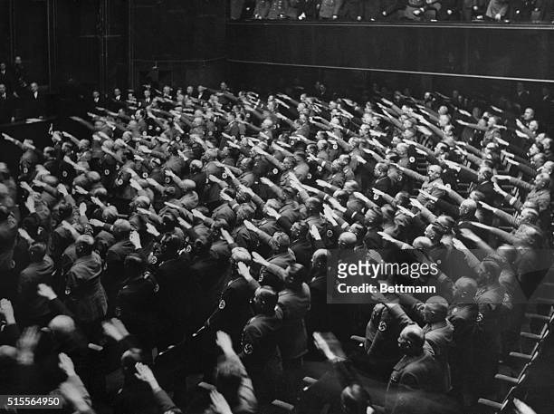 Delegates to the Reichstag tender the Nazi salute during the playing of the National Anthem after Fuhrer Hitler's speech denouncing the Locarno Pact...