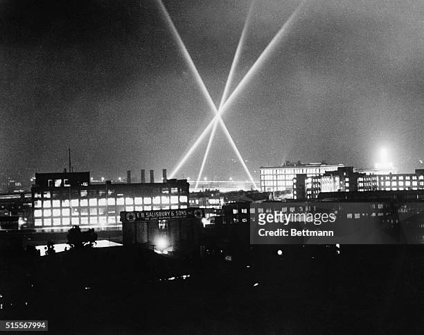 The beams of three great 60 inch army antiaircraft searchlights undergoing a test from a defense pattern in the sky above the main works of the...