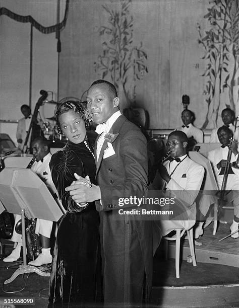 Jesse Owens, whose flying feet are more at home at a cinder track, goes to town with Mrs. Owens at the opening of the Cotton Club, in New York City.