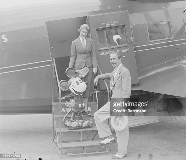 Stewardess Izola Readle takes tickets from cartoonist Walt Disney, with his creation Mickey Mouse, in Newark, New Jersey as they board an airplane on...