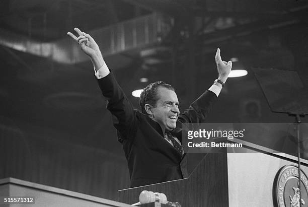 Republican presidential nominee Richard M. Nixon raises both hands in his trademark double "victory" sign as he greets a crowd of cheering delegates...