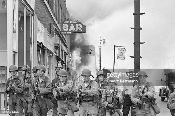 Detroit :Tough-looking Michigan National Guardsmen push rioting Negroes back from a burning building with fixed bayonets on Detroit's riot-torn west...