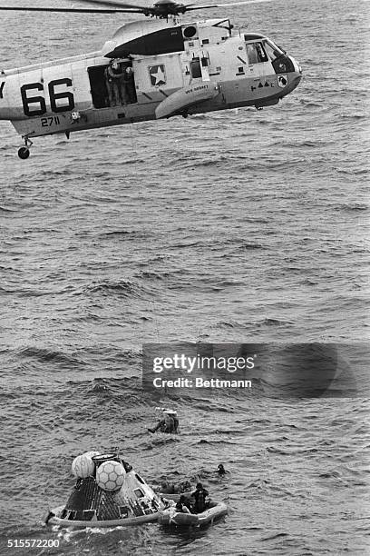 ABOARD THE USS HORNET: A RESCUE HELICOPTER LIFTS THE FIRST APOLLO 11 ASTRONAUT FROM THE RAFT AFTER THE SPLASHDOWN IN THE PACIFIC, THE OTHER TWO...