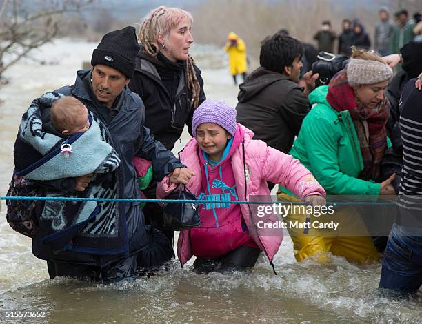 Migrants cross a river after leaving the Idomeni refugee camp on March 14, 2016 in Idomeni, Greece. The decision by Macedonia to close its border to...