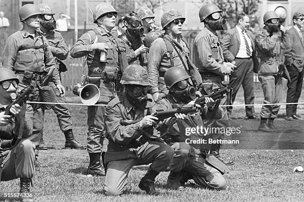 Masked national guardsmen fire barrage of tear gas into crowd of demonstrators on campus of Kent State University May 4th. When the gas dissipated,...