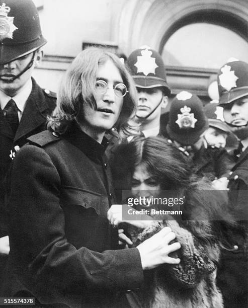 Beatle John Lennon holds his girlfriend, artist Yoko Ono, as they leave a London court hearing after facing charges of possessing marijuana and...