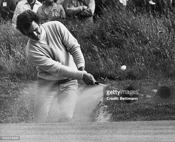 Tony Jacklin of Britain raises the dust as he blasts out of a bunker by the 15th green during the third round of the British Open Golf Championship...