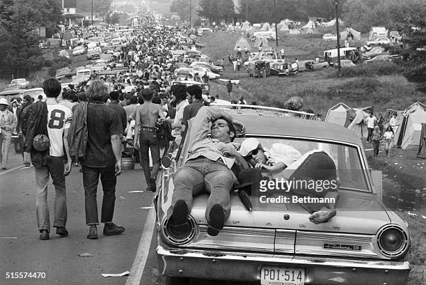On foot, in cars, atop cars, young people leave the great love-in of the sixties, the Woodstock Music Festival. Three hundred thousand young people...