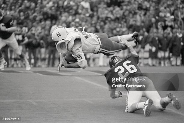 Nebraska's running back Jeff Kinney , his torn jersey exposing his shoulder pads, gets tripped up by Oklahoma tackler Larry Roach for a gain of two...