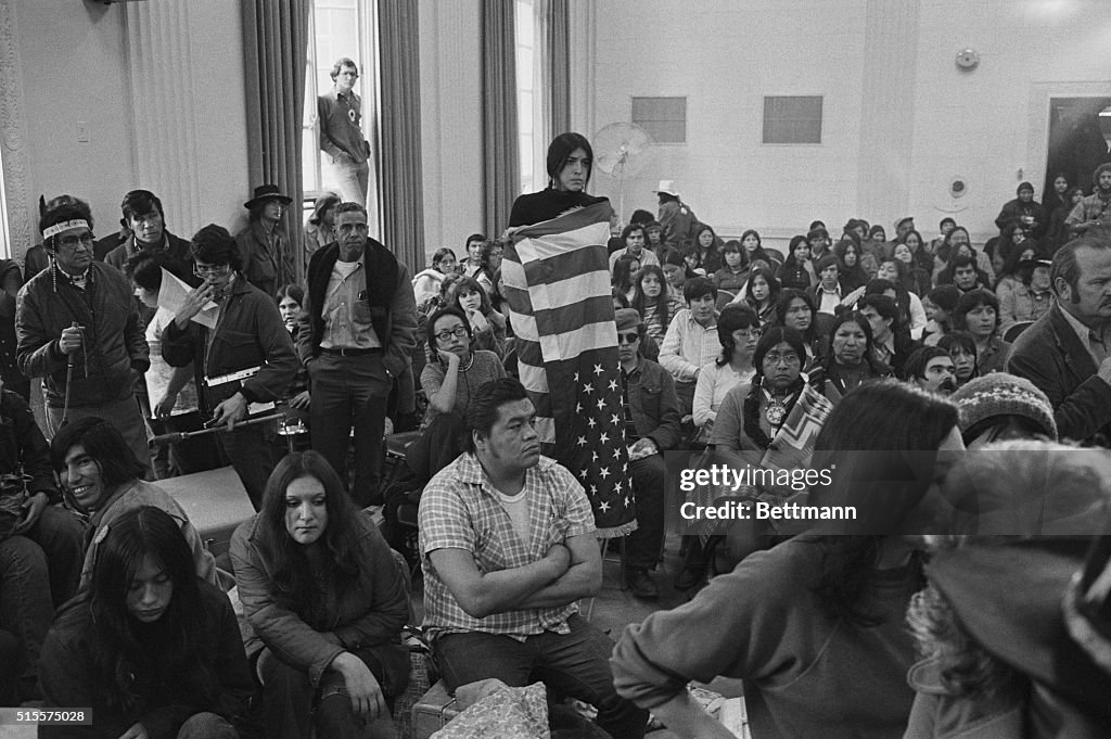 Native Women Protesting American Indian girl is wrapped in an upside down American flag as ...