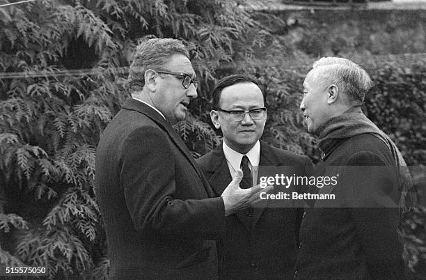 An interpreter stands between White House Advisor Henry Kissinger and Hanoi's senior representative Le Duc Tho as they converse in the garden of a...
