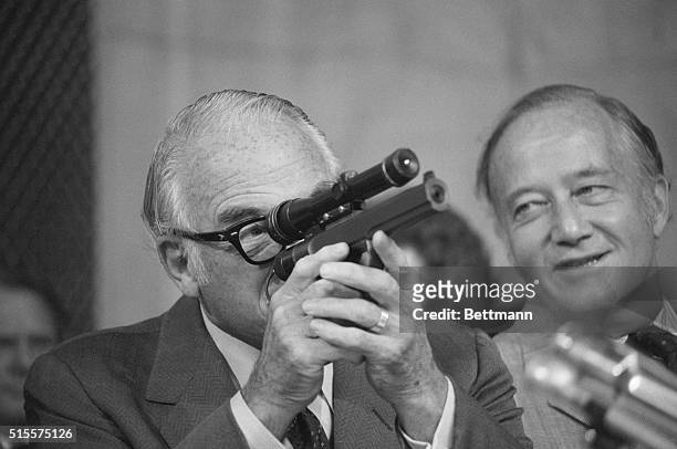 Washington:Sen.Barry Goldwater, R-Ariz., sights through a telescope on a dart gun, displayed by CIA Director William Colby to the Senate Select...