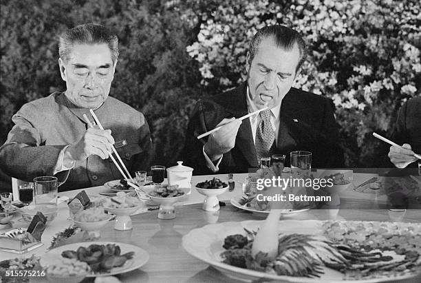 Pres. Richard Nixon digs in with chopsticks as he sits beside Chinese Premier Chou En-lai during farewell banquet on the eve of Nixon's departure...