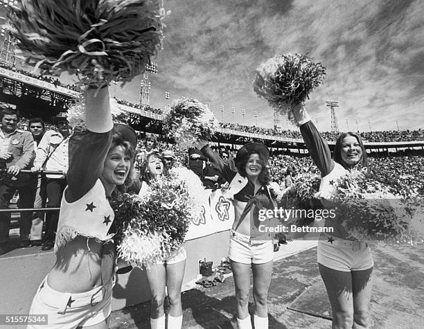 Four Dallas Cowboys cheerleaders cheer their team in the 1976 Super Bowl in Miami. Many men leer from the stands behind them.