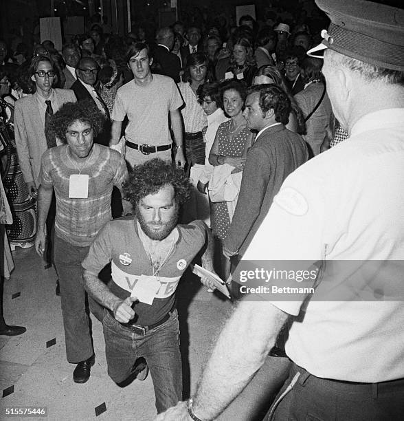 Miami Beach: Crashing the scene is Jerry Rubin, front, and Abbie Hoffman as they dash past guards at the Democratic Telethon. Both were wearing...