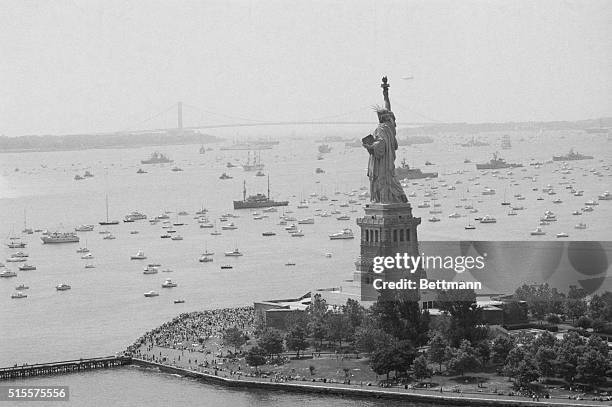Long line of ships sails past Statue of Liberty in New York Harbor here 7/4 as they take part in Operation Sail during Bicentennial celebrations.
