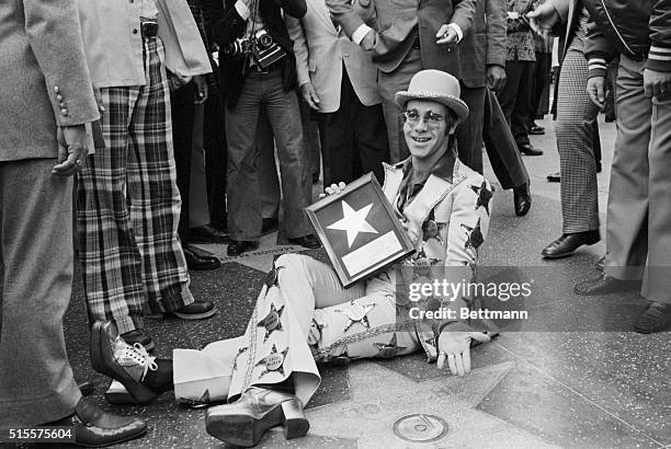 10/24/75-HOLLYWOOD: ROCK STAR ELTON JOHN RELAXES ON THE SIDEWALK OF HOLLYWOOD BLVD. AS HIS GOLD STAR WAS DEDICATED IN WALK OF FAME HERE 10/23. HE...