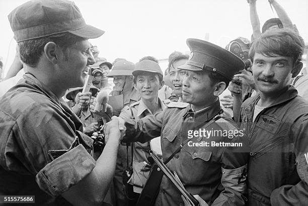 Saigon, Vietnam: N. Vietnamese Lt. Col. Bui Tin , official spokesman for the N. Vietnamese delegation to the JMC, shakes hands with unidentified...