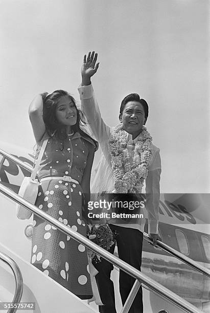 Phillipine President Ferdinand E. Marcos and daughter Imee wave to crowd before boarding a plane for Peking 6/7. President Marcos and First Lady...