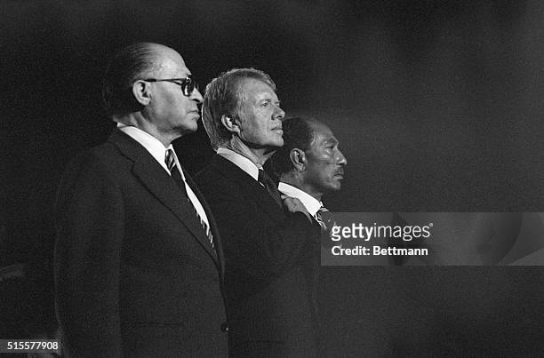 Israeli Prime Minister Menachem Begin, President Carter and Egyptian President Anwar Sadat stand together during the playing of the national anthem...