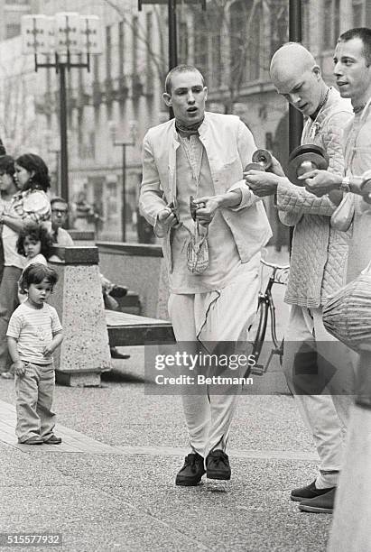 Boy is intrigued by the chanting and dancing of members of the Hare Krishna movement as the religious group performs in the downtown area 4/19 to...