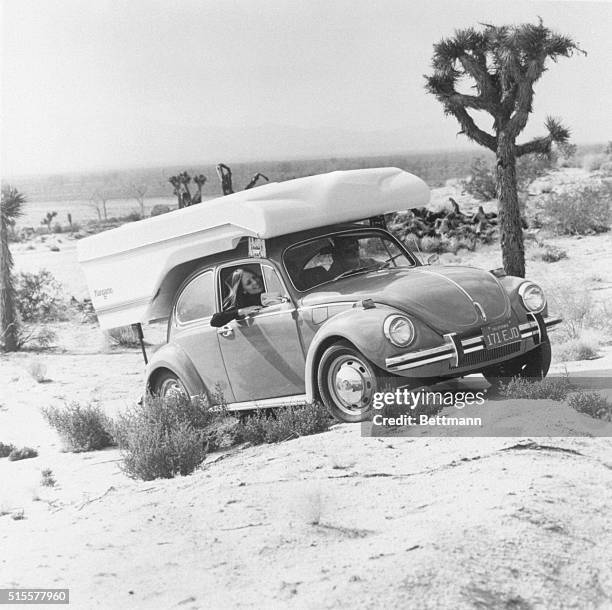 Passenger smiles inside a Volkswagen Beetle traveling with a Kangaroo camper through the desert. The camper, produced by Compact, Inc., is the first...