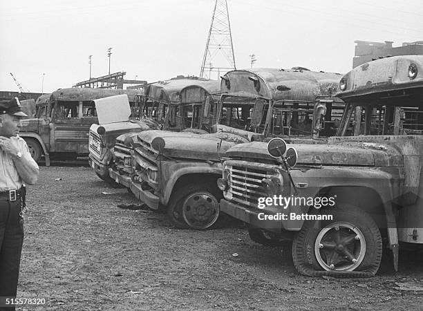 Pontiac, Michigan: A Pontiac policeman examines some of the ten school buses destroyed late Aug. 30 by dynamite and fire in a school bus depot here....