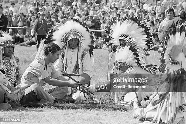 Prince Charles smokes a peace pipe with medicine man Ben Calfrope during a re-enactment ceremony of a treaty signed between the Blackfoot Confederacy...