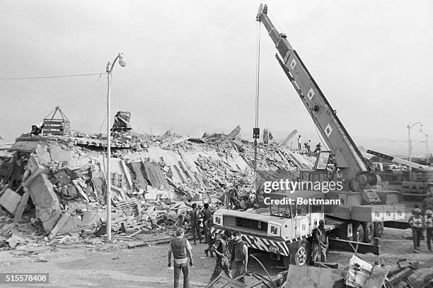 Workers use a large crane to move the rubble of a US marine barracks in Beirut, Lebanon which collapsed after a truck filled with explosives crashed...