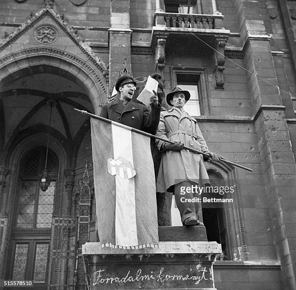 Budapest, Hungary: Standing by a Hungarian Nationalist flag, one of the leaders of the uprising against Soviet domination addresses a crowd there...