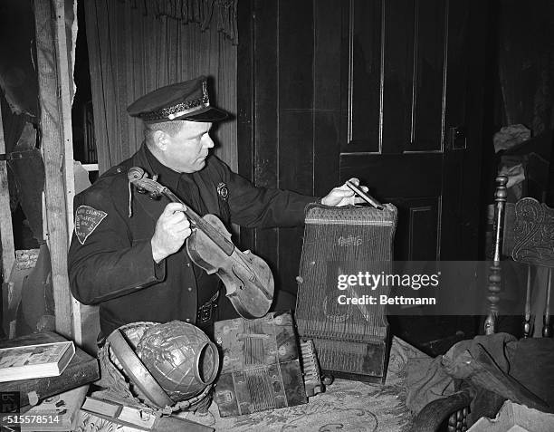 Plainfield, WI: Trooper Dave Sharkey looks over some of the musical instruments found in the home of bachelor farmer Ed Gein suspected grave robber...