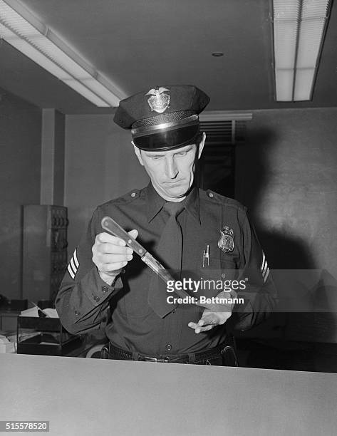 Hollywood, California: Police Sgt. Russel R. Peterson examines the eight-inch carving knife that was reportedly used in the fatal stabbing of...