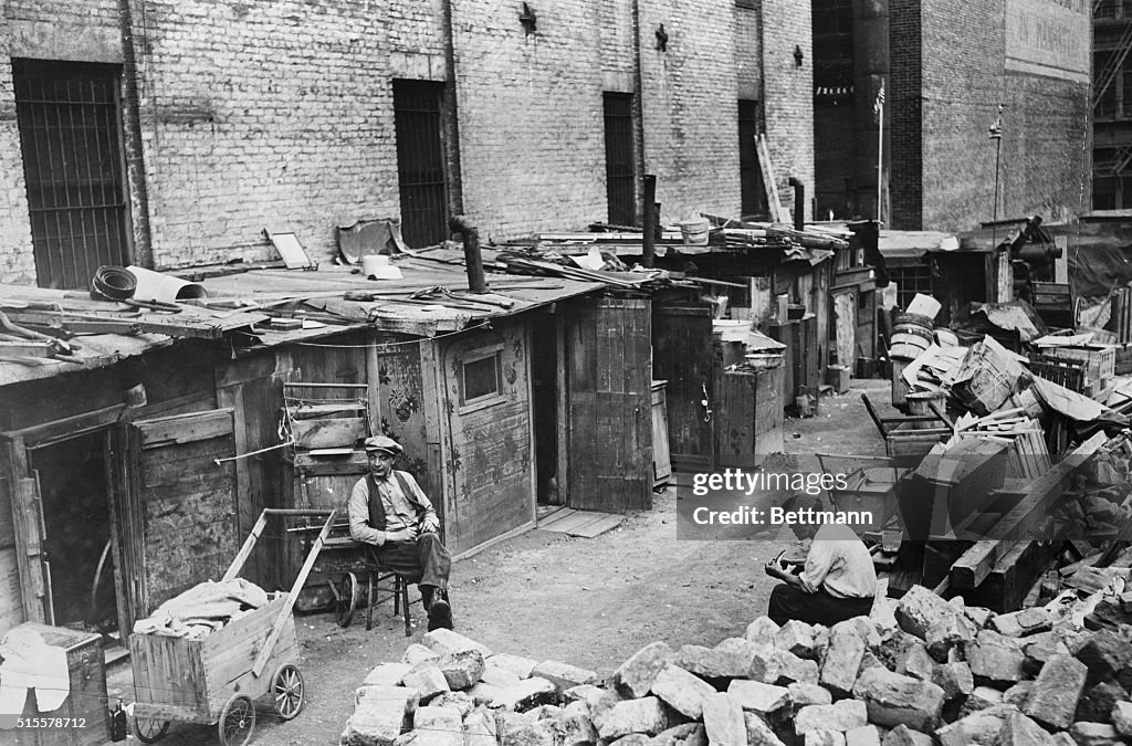 Stacks Slums Men sit outside their shacks in a New York slum in the early 1900s ...