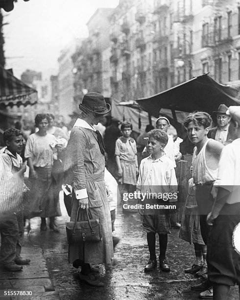 New York, NY: Lower New York street scene showing underprivileged children speaking to visiting nurse from Henry Street settlement house. Photograph,...