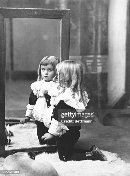 Little boy dressed in a Lord Fauntleroy costume gazing into a mirror. Photograph by Joseph Pennell, 1898.