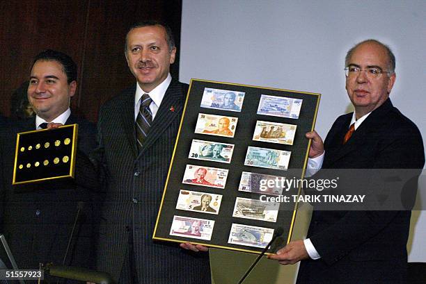 Turkish Prime Minister Recep Tayyip Erdogan holds with the president of Turkey's Central Bank, Sureyya Serdengecti , a board featuring the new...